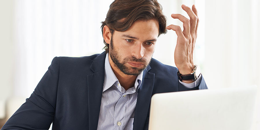 Business Man At Computer Confused With Hand Up