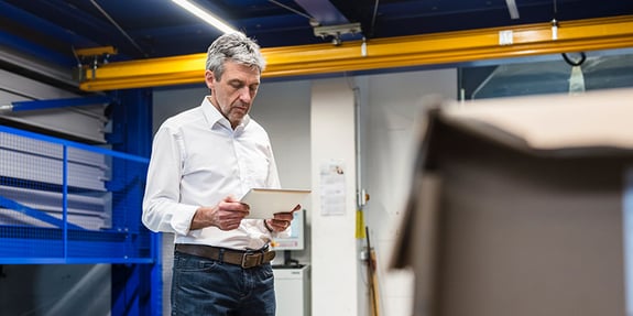 Man Looking At Tablet On Machine Floor