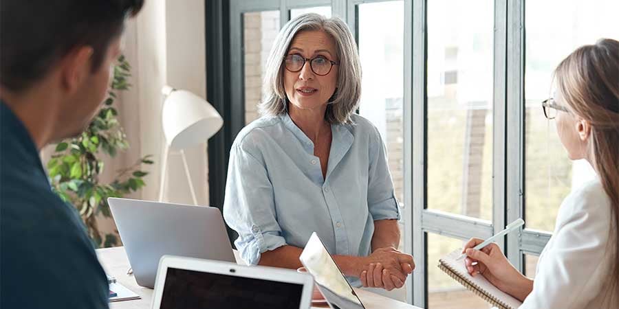 Senior Woman Manager Talking With Team Around Table Together