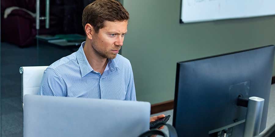 Serious younger manager sitting at his desk with a perplexed expression