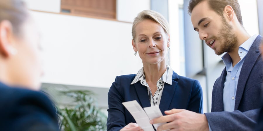 Two colleagues looking at two pieces of paper together. 