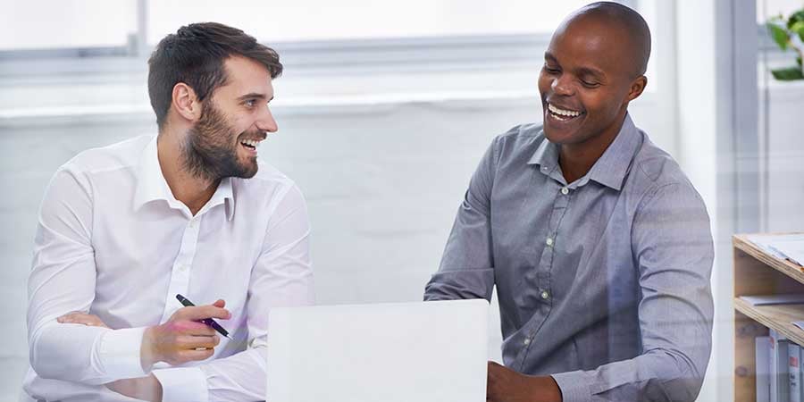 Two Men Laughing Together At Computer