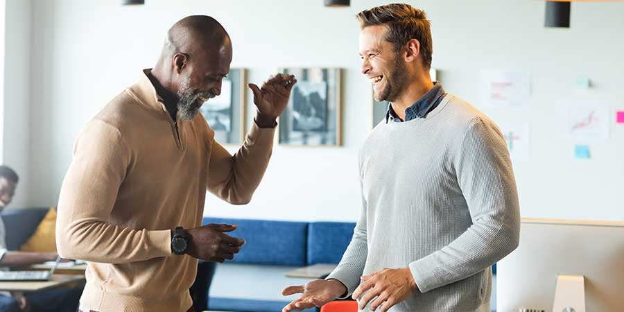 Two senior sales managers laughing with large smiles while giving each other high-fives